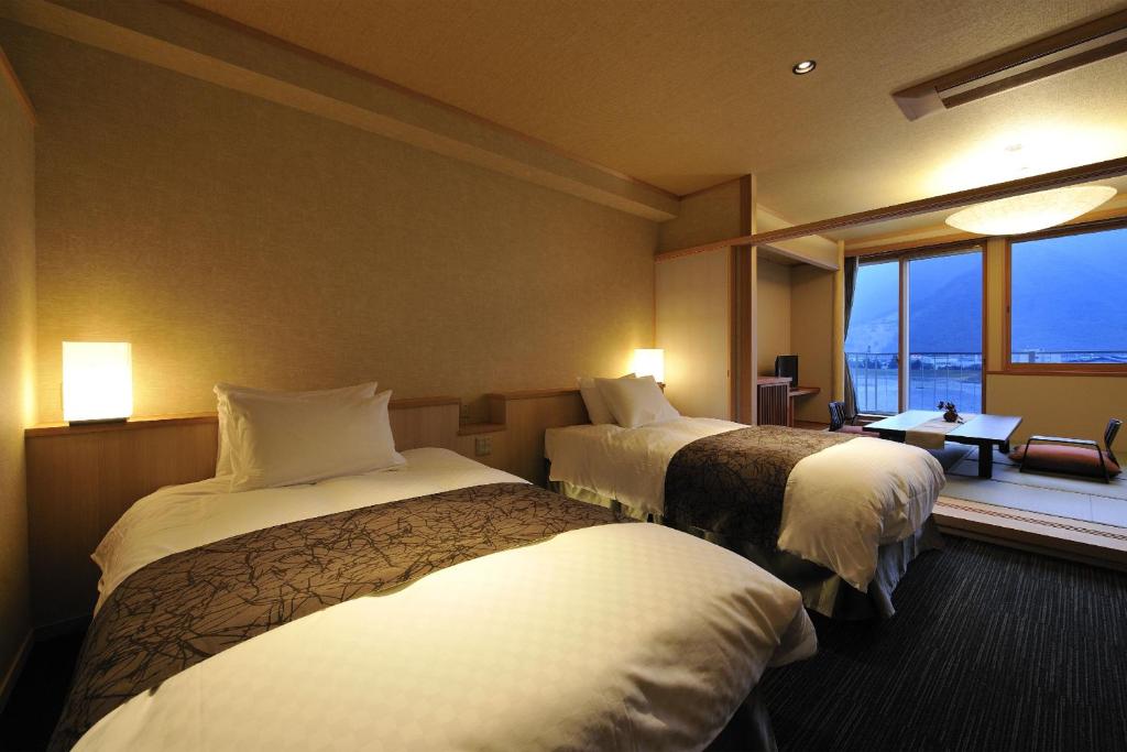 a hotel room with two beds and a window at Hotel Seifuen in Chikuma