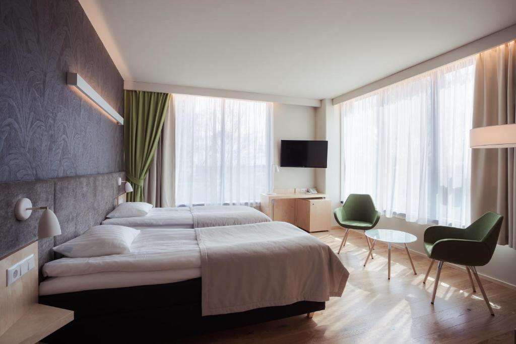 a bedroom with a large bed and two green chairs at Hotel Tartu in Tartu