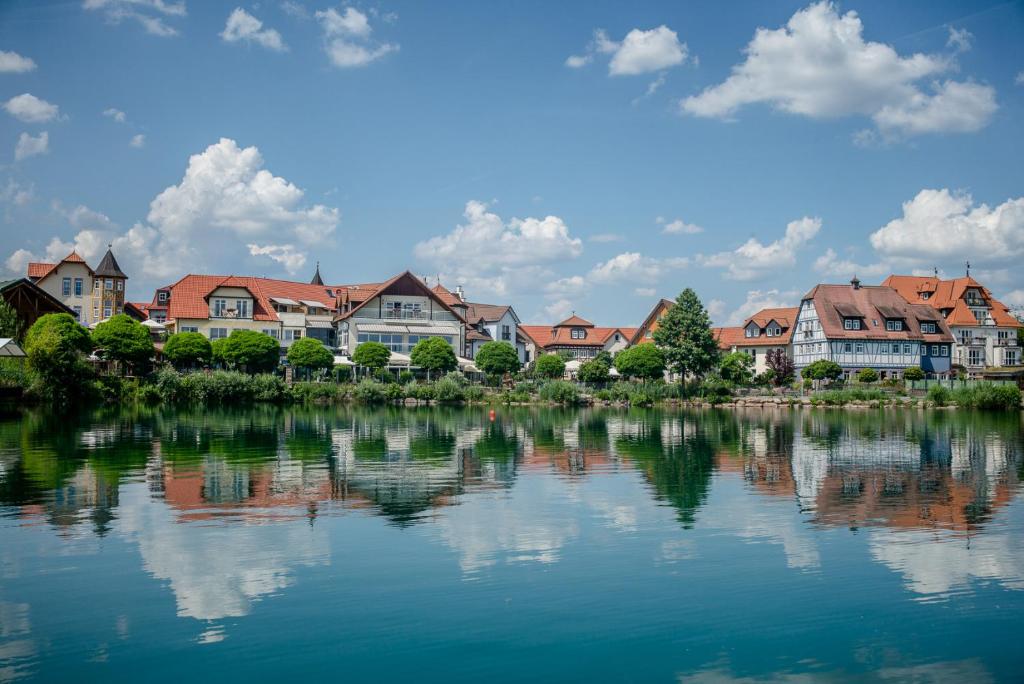 um grupo de casas ao lado de uma massa de água em Seehotel Niedernberg - Das Dorf am See em Niedernberg