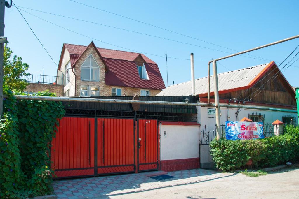 a house with a red gate and a building at Sakura Guesthouse in Bishkek