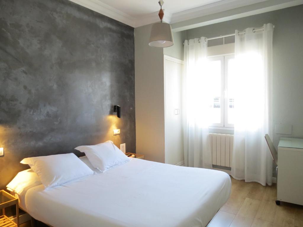 1 dormitorio con cama blanca y ventana en Pensión Don Claudio en Bilbao