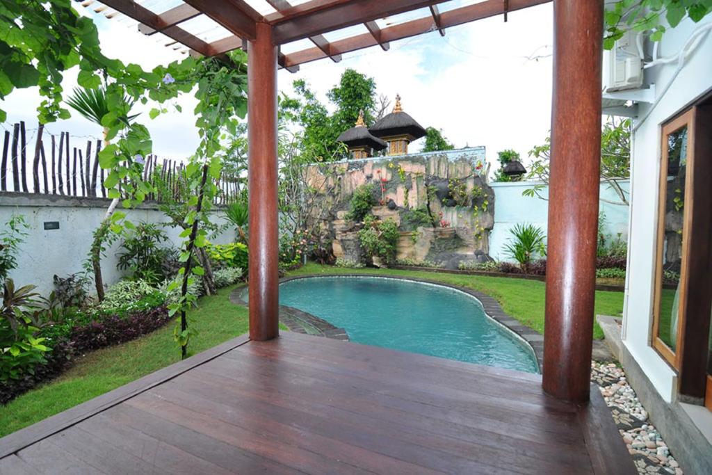 a patio with a swimming pool and a waterfall at Kandava Villa in Jimbaran