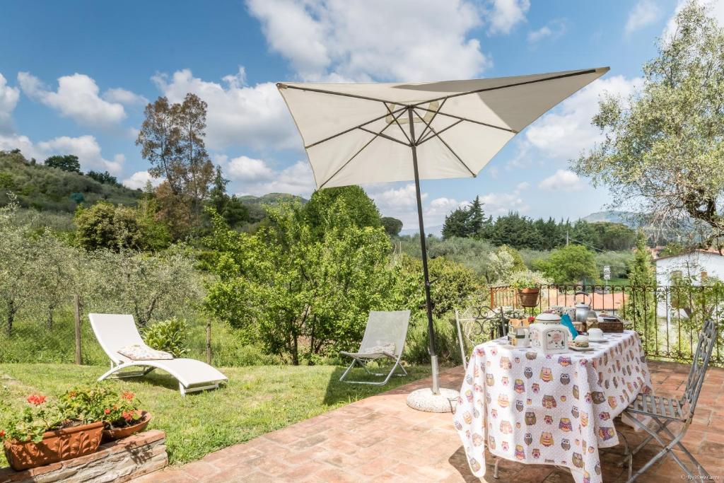 uma mesa e um guarda-sol num jardim em Le Civette e L'Upùpa Country Houses em San Quirico di Moriano