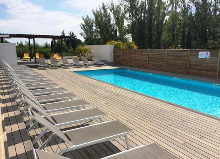 una piscina con sedie a sdraio accanto a una terrazza in legno di Les Terrasses D'Aix - Studio avec Grande Terrasse privée ad Aix en Provence