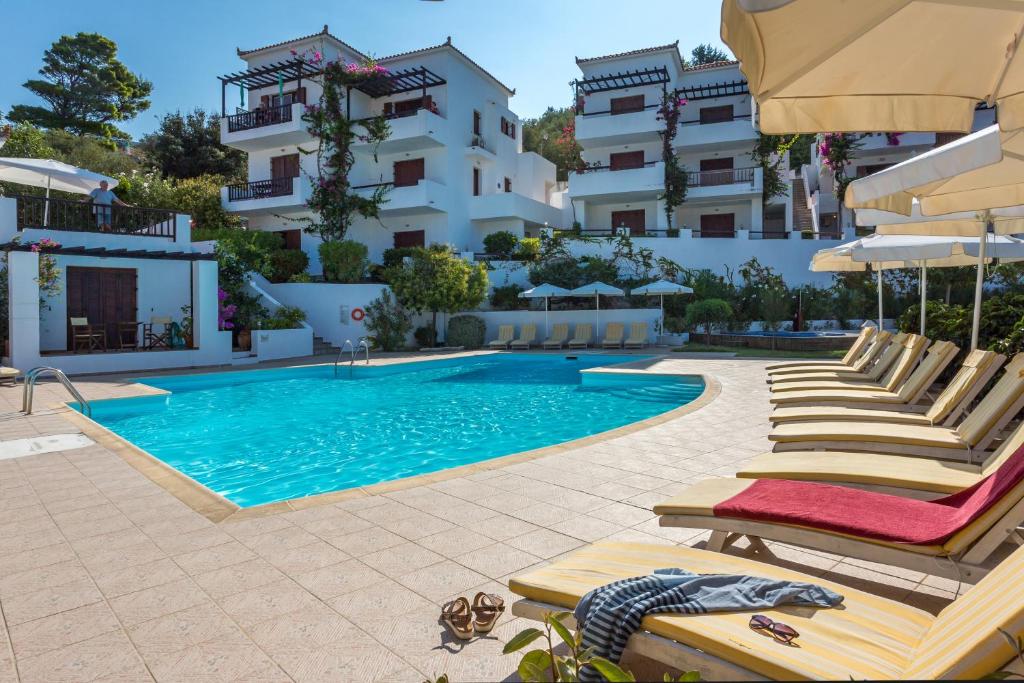 a swimming pool with lounge chairs and a hotel at Maistros Suites - Péra in Skopelos Town