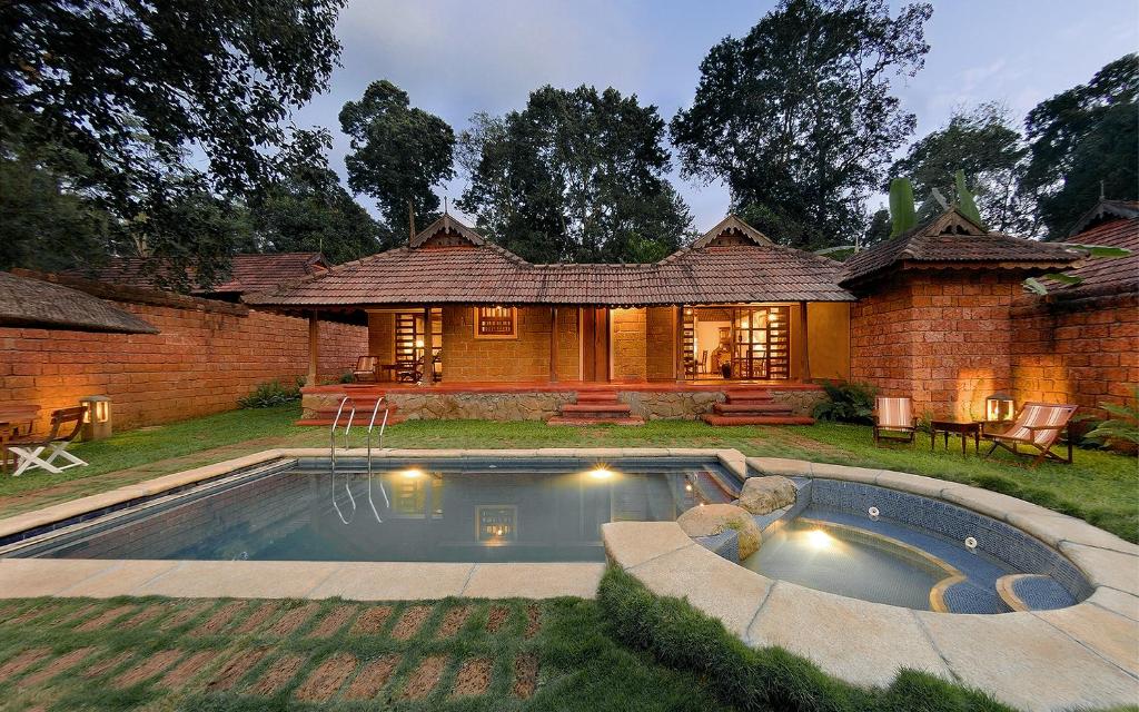 a house with a swimming pool in the yard at Evolve Back Coorg in Siddapur