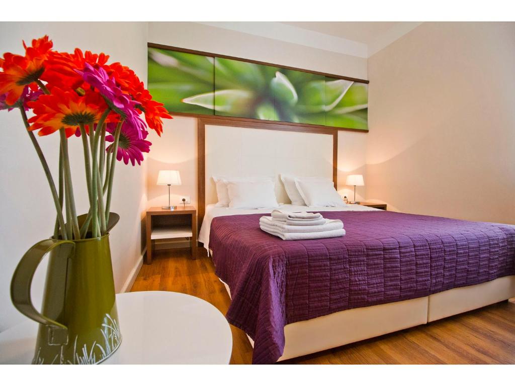 Un dormitorio con una cama morada con un jarrón de flores en Bastion Luxury Rooms, en Split