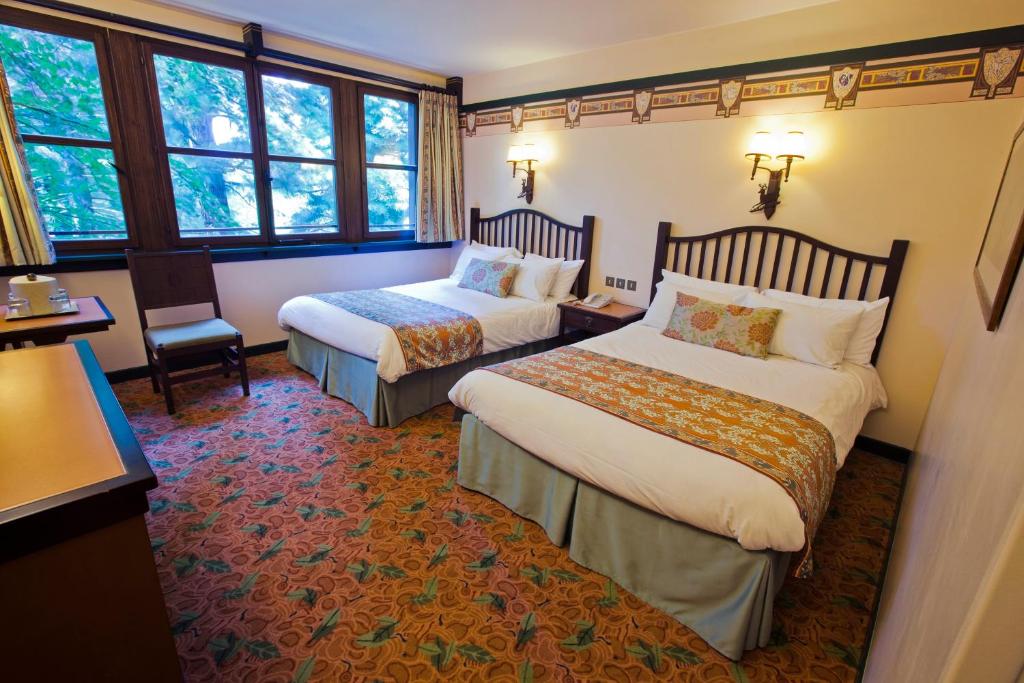 una habitación de hotel con 2 camas y una silla en Disney Sequoia Lodge, en Coupvray