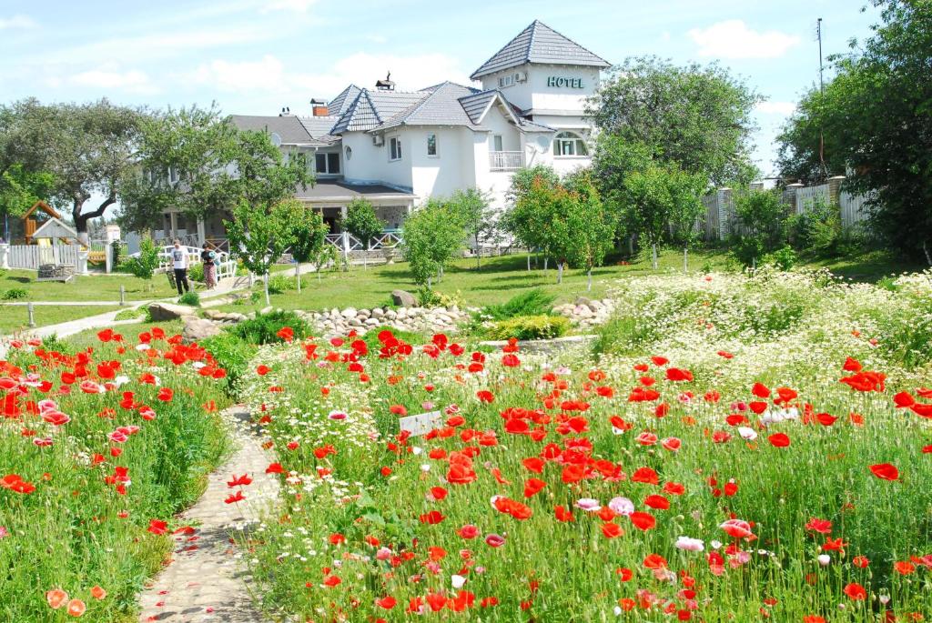 a field of red and white flowers in front of a house at Maison Blanche Ecohousе in Mytnitsa