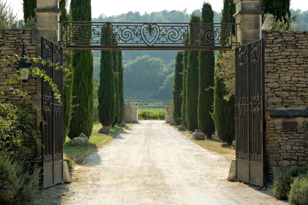 an entrance to a road with an archway with trees at Hostellerie Le Roy Soleil in Ménerbes