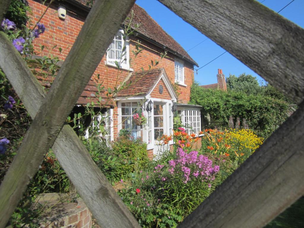 ein Haus mit einem Garten mit Blumen davor in der Unterkunft Vine Cottage in Farnham