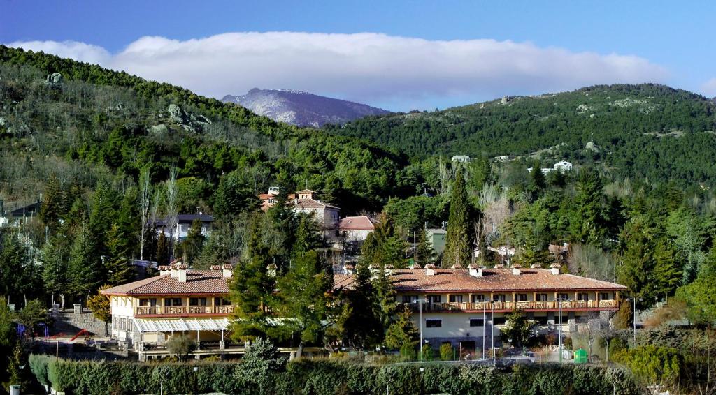 un gran edificio en medio de una montaña en Hotel Rural Spa & Wellness Hacienda Los Robles, en Navacerrada