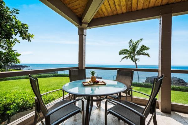 un patio con mesa, sillas y el océano en Keauhou Kona Surf and Racquet Club 2-204 en Kailua-Kona