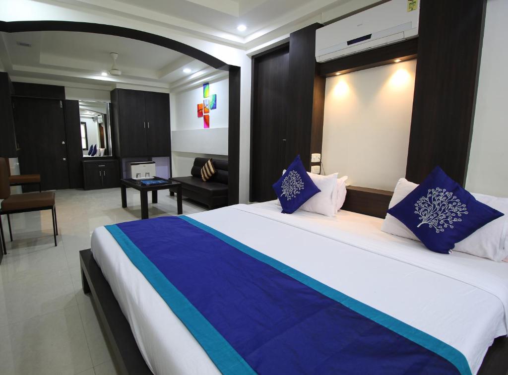 a bedroom with a large bed with blue and white pillows at Hotel Nova Cross Road in Rajkot