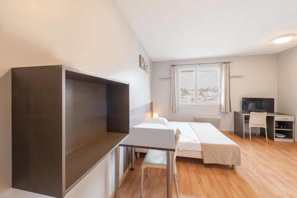 een slaapkamer met een bed, een bureau en een televisie bij City Résidence Marseille in Marseille