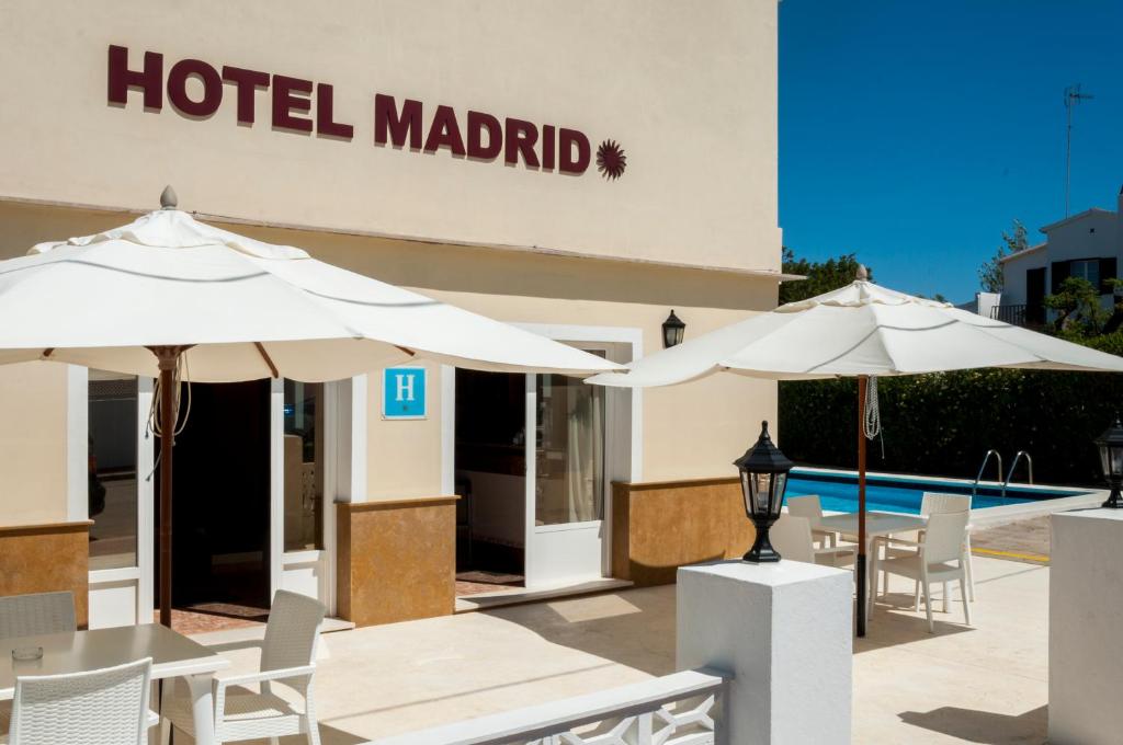 a hotel madrid with tables and umbrellas next to a pool at Hotel Madrid in Ciutadella