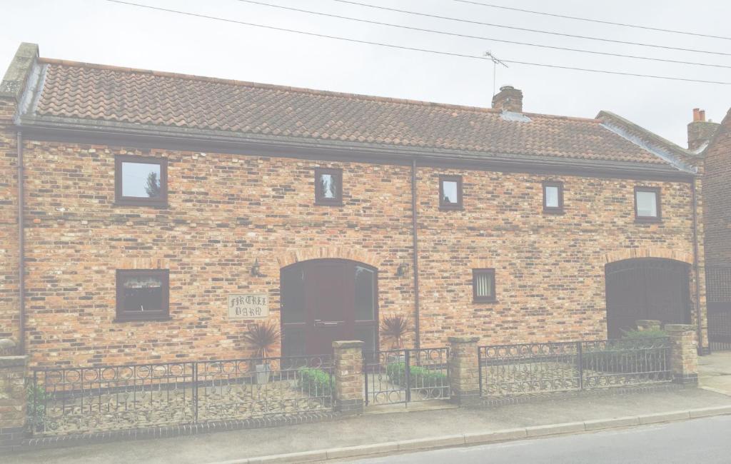 a brick building with two large doors and a fence at Fir Tree Barn in Pollington