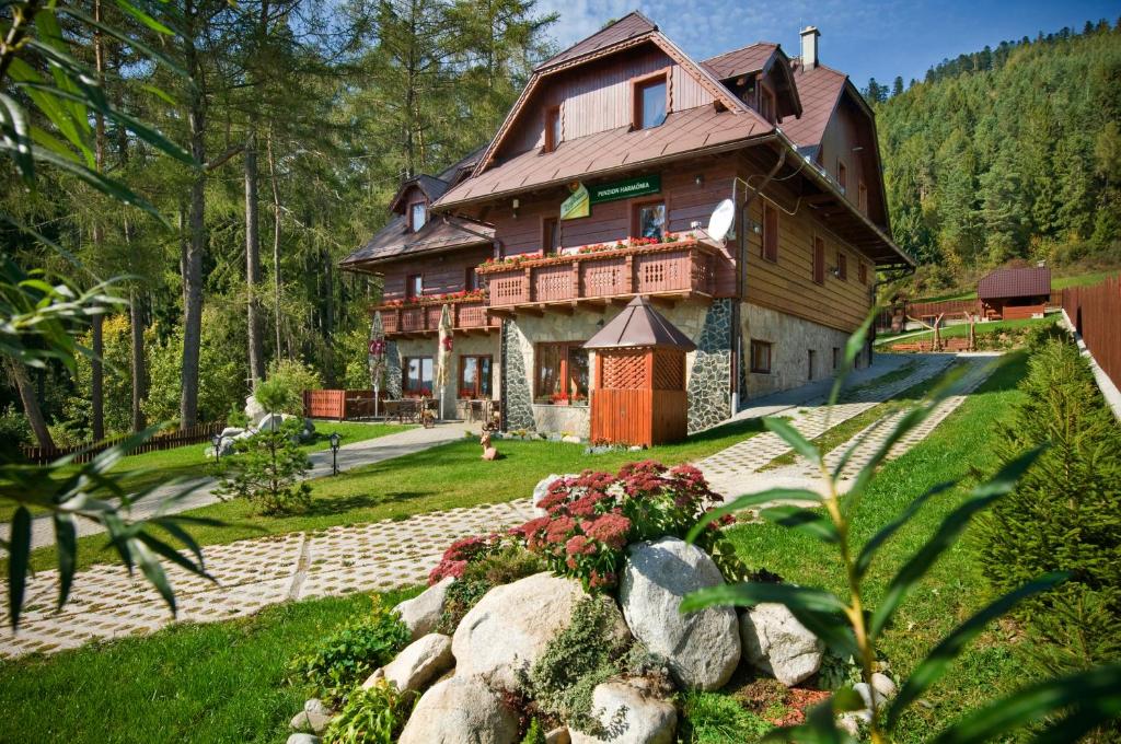 a large wooden house with a garden in front of it at PENZIONHARMONIA eu in Lendak