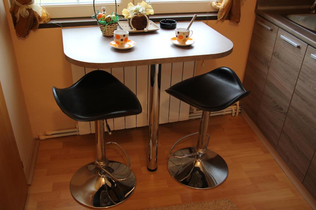 a small kitchen with a small table and two stools at Rajski vrt in Vrdnik