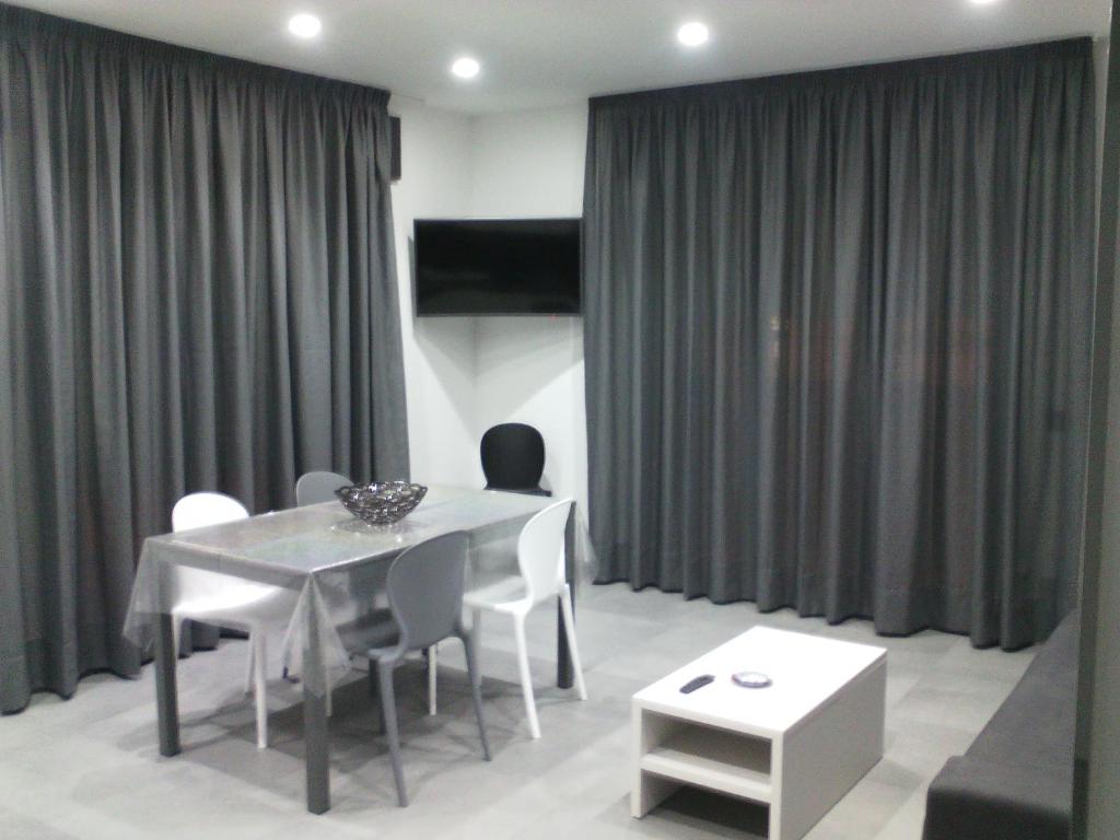 a dining room with a table and chairs and curtains at Diana Apartment in Valderice