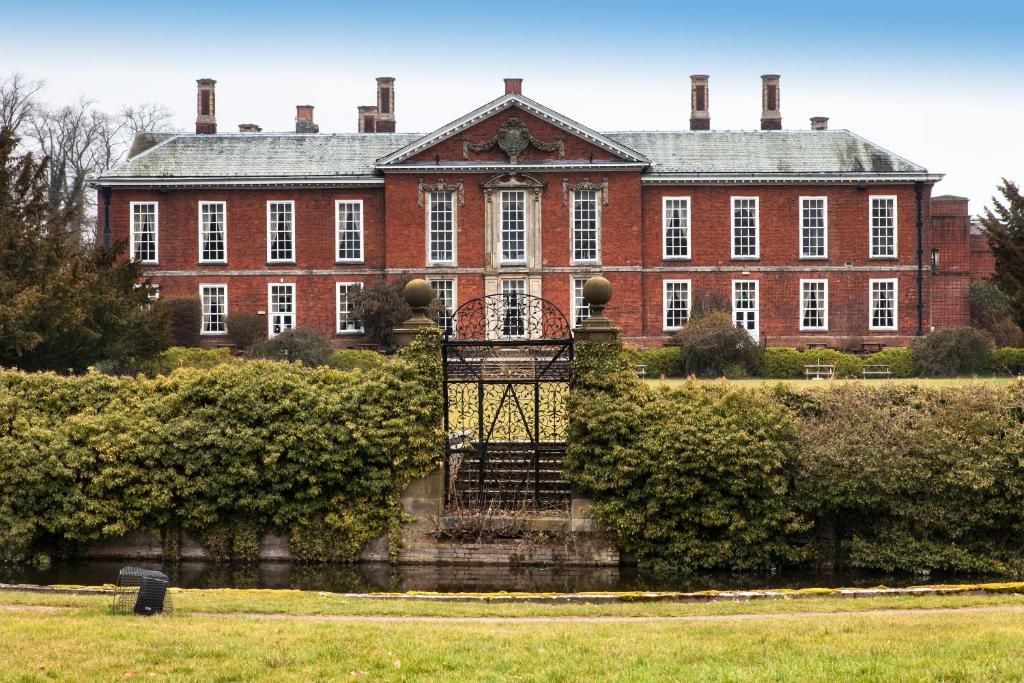 ein großes rotes Backsteingebäude mit einem Tor davor in der Unterkunft Bosworth Hall Hotel & Spa in Market Bosworth