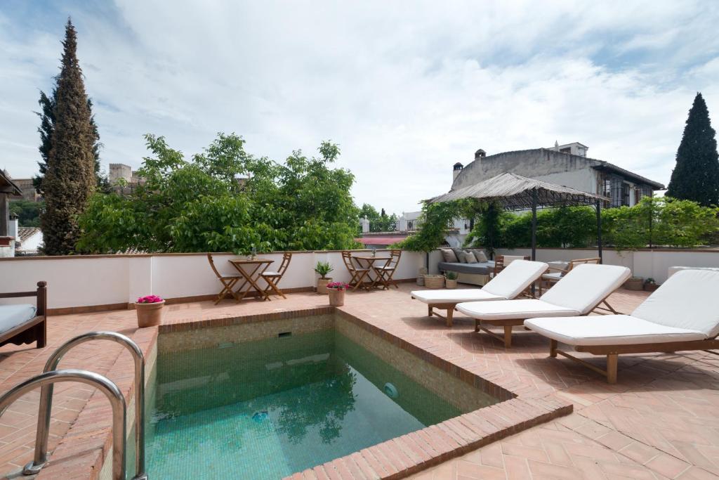 a swimming pool with chaise lounge chairs next to a house at Casa Bombo in Granada