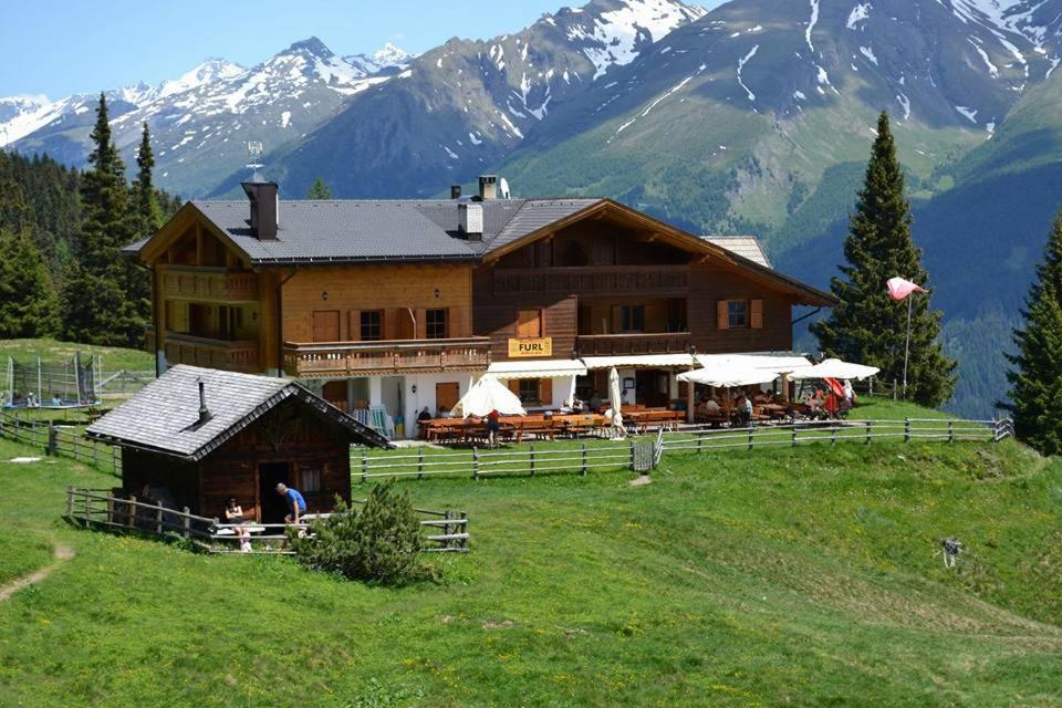 a large building on a hill with mountains in the background at Gasthaus Furlhütte in Vipiteno