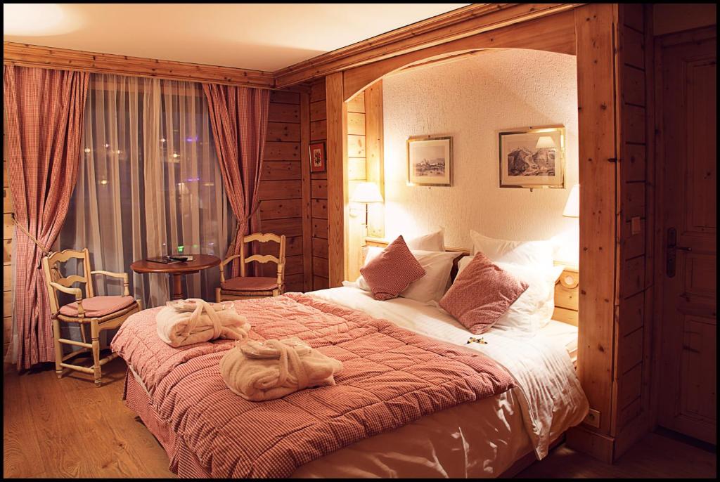 a bedroom with a large bed with towels on it at Chalet-Hôtel La Marmotte, La Tapiaz & SPA, The Originals Relais in Les Gets