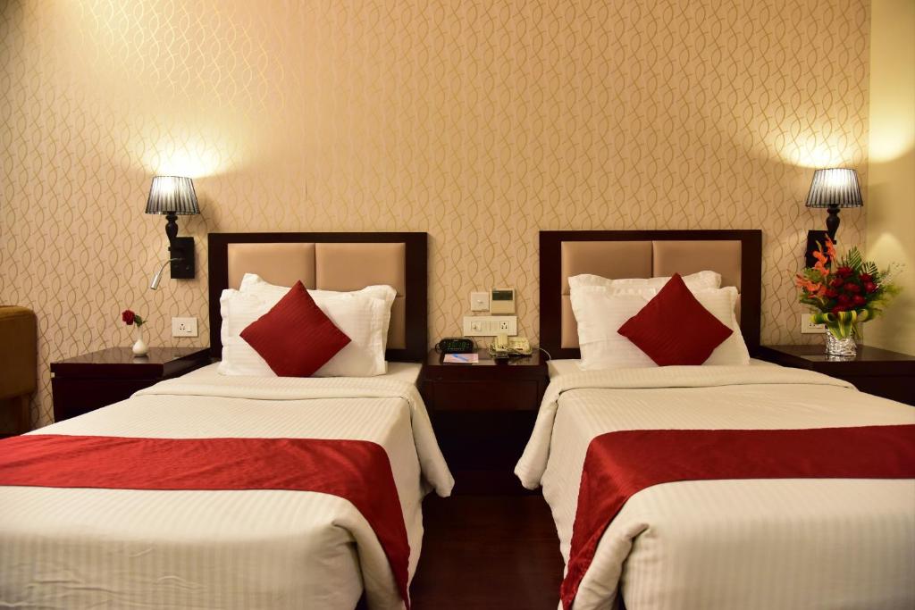 a hotel room with two beds with red pillows at Hotel JIVA in Jamshedpur