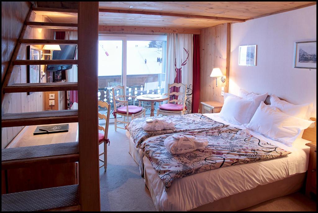 a bedroom with a bed with a ladder and a table at Chalet-Hôtel La Marmotte, La Tapiaz & SPA, The Originals Relais in Les Gets