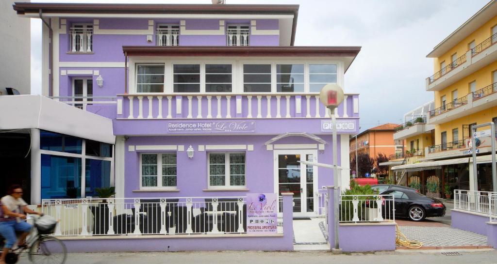 ein violettes Gebäude mit einer Person, die ein Fahrrad davor reitet in der Unterkunft Residence Hotel Le Viole in Rimini