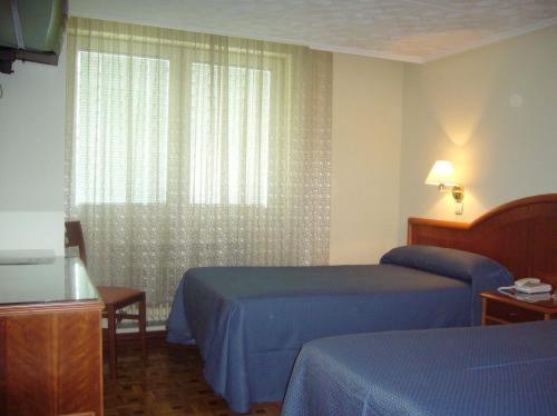 a hotel room with two beds and a window at Hotel Buenos Aires in Villafría de Burgos