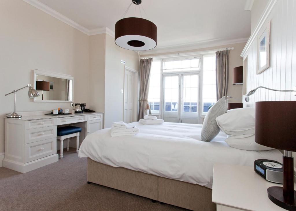 a white bedroom with a large bed and a desk at The Marine in Whitstable