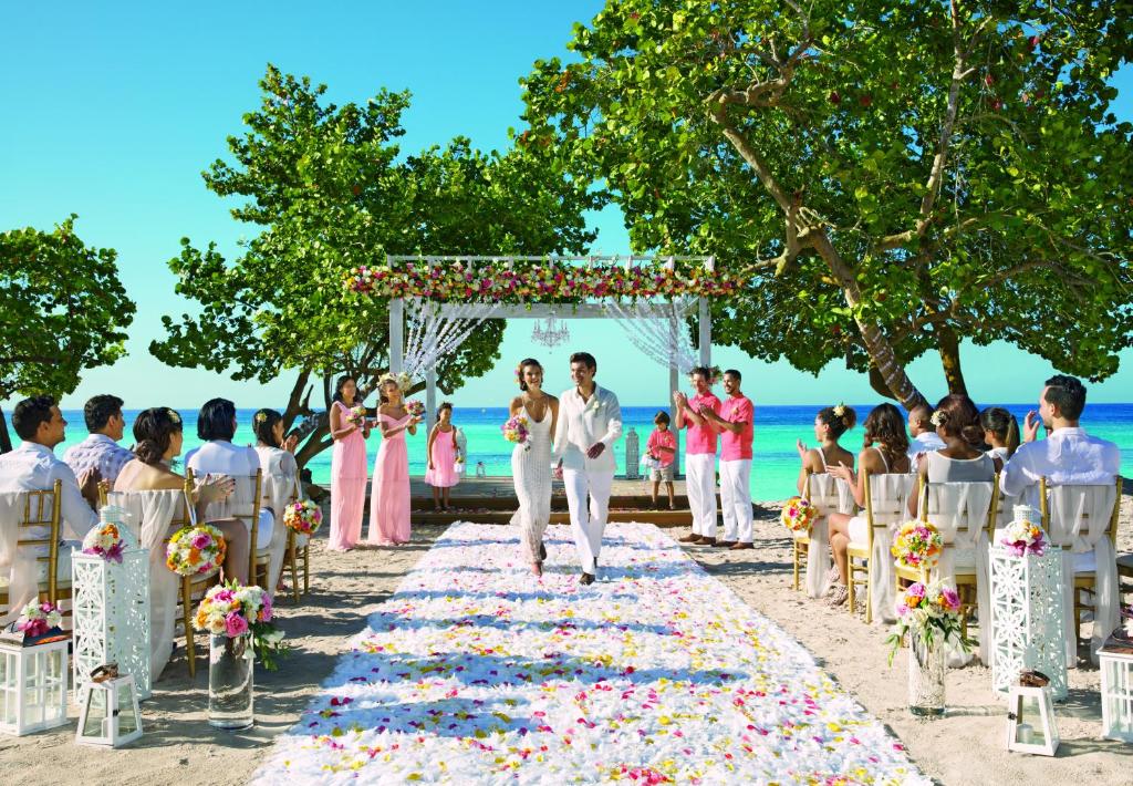 a bride and groom walking down the aisle at a wedding on the beach at Dreams Dominicus La Romana Resort & Spa in Bayahibe