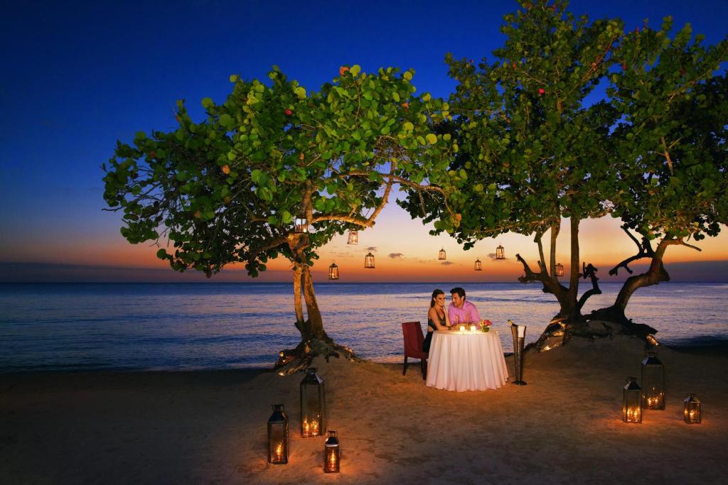 a bride and groom sitting at a table on the beach at Dreams Dominicus La Romana Resort & Spa in Bayahibe