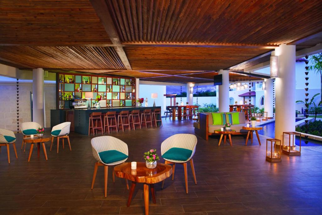 a restaurant with chairs and tables and a bar at Dreams Dominicus La Romana Resort & Spa in Bayahibe