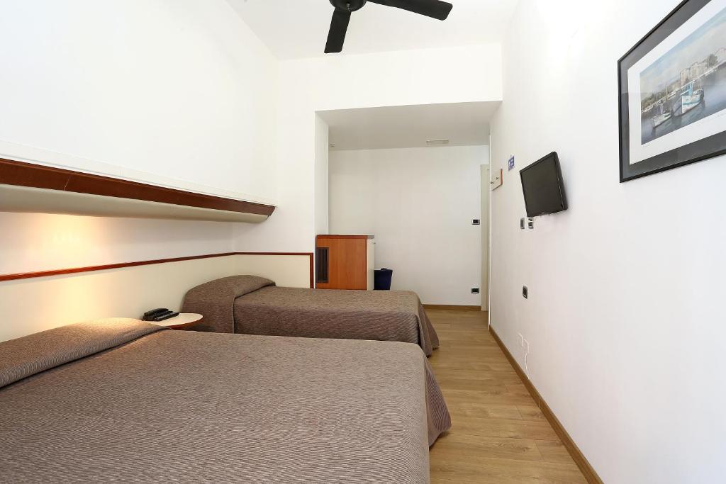 a hotel room with two beds and a tv at Hotel Corticella in Bologna