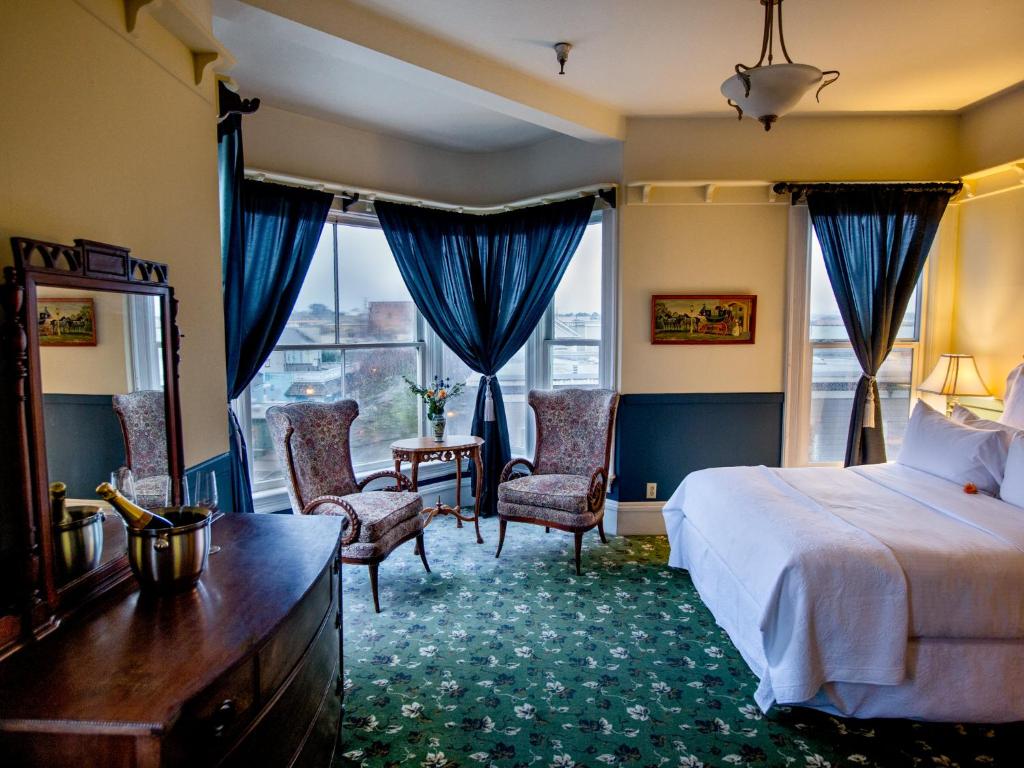 a bedroom with a bed and two chairs and a window at The Inn at 2nd & C in Eureka