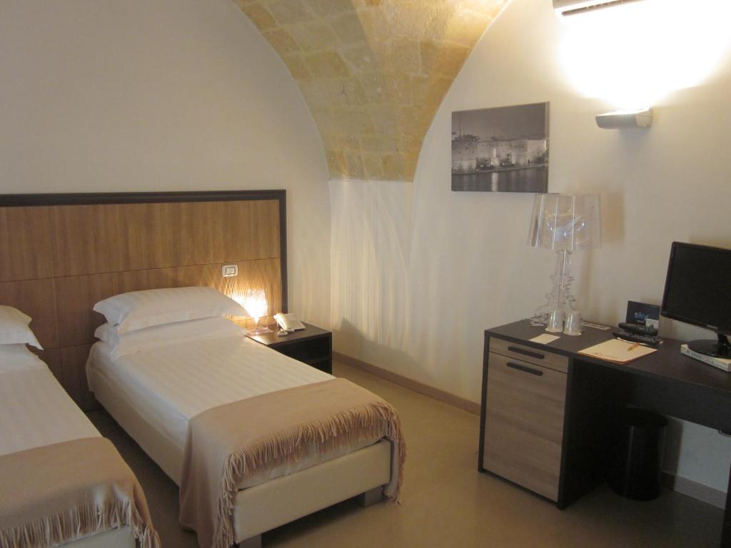 a bedroom with two beds and a desk with a computer at Albergo Del Sole in Taranto