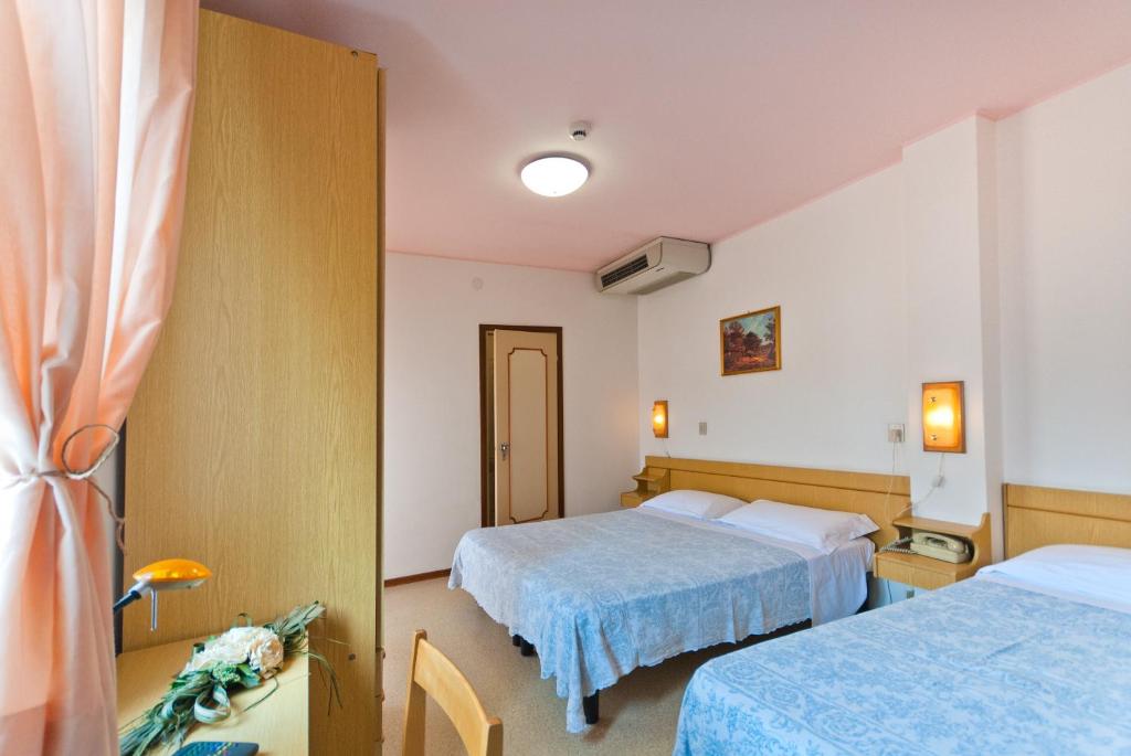 una camera d'albergo con due letti e una finestra di Hotel Bianchi a Bibione