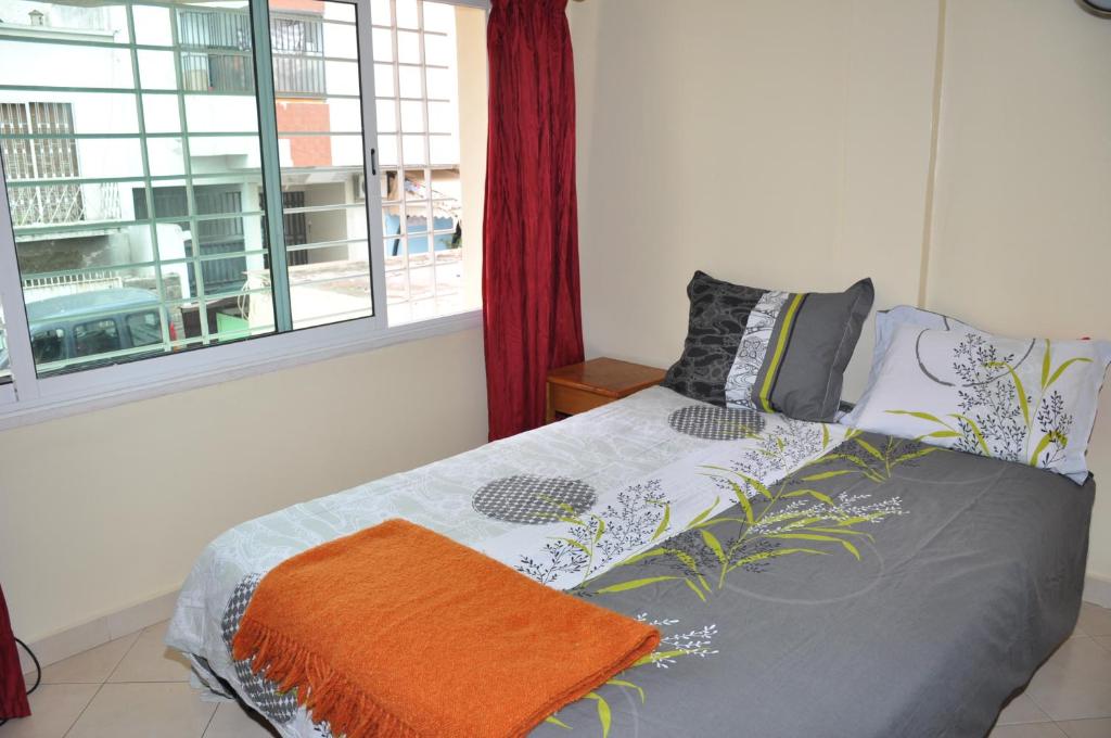 a bedroom with a bed with an orange blanket and a window at Rabat Appartement Agdal in Rabat
