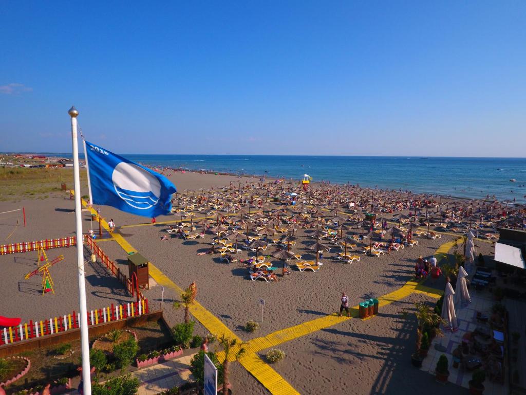 a beach with a large crowd of people and a flag at MCM Camping in Ulcinj