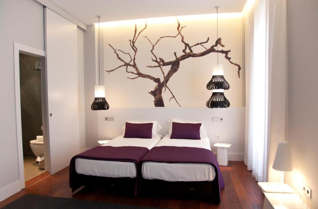 um quarto com uma cama com uma árvore na parede em Khu Hotel em Granada