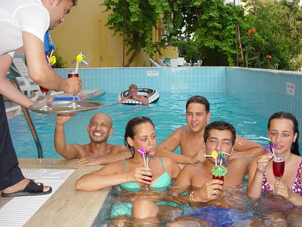 アランヤにあるAysev Hotelのスイミングプールでドリンクを飲みながら座る人々