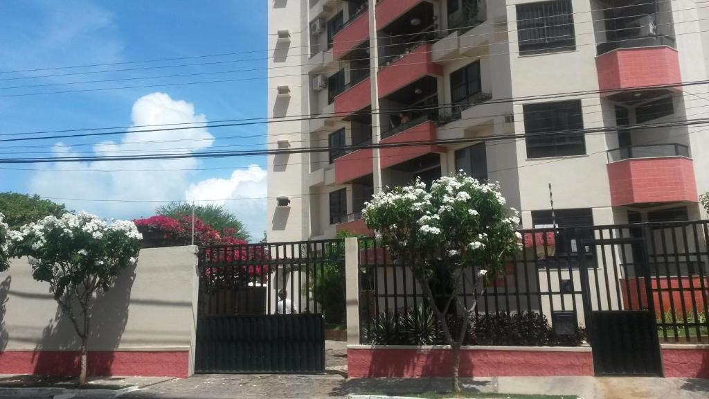 un edificio con una valla y árboles delante de él en Apartamento Atalaia Aracaju, en Aracaju