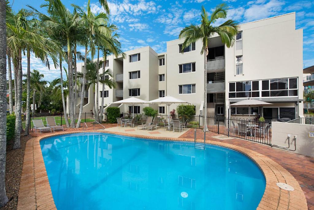 
a large swimming pool in front of a large building at Joanne Apartments in Caloundra
