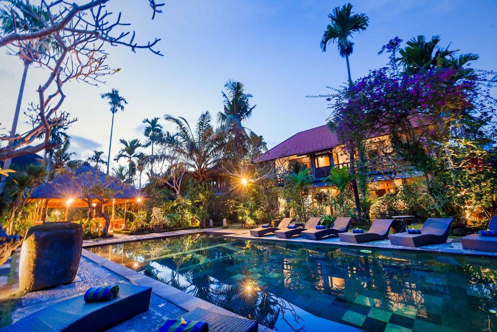 a resort pool with lounge chairs and a building at Ubud Inn Cottage by Prasi in Ubud