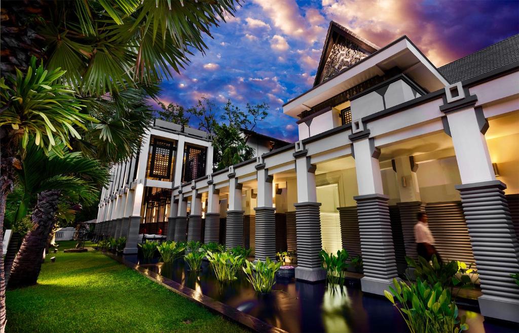 
a large building with trees and palm trees in front of it at Shinta Mani Angkor & Bensley Collection Pool Villas in Siem Reap
