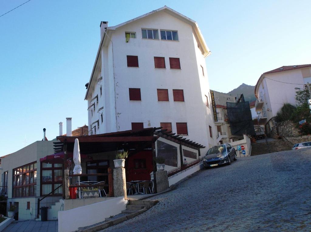 un alto edificio bianco con una macchina parcheggiata di fronte di Estrela a Manteigas