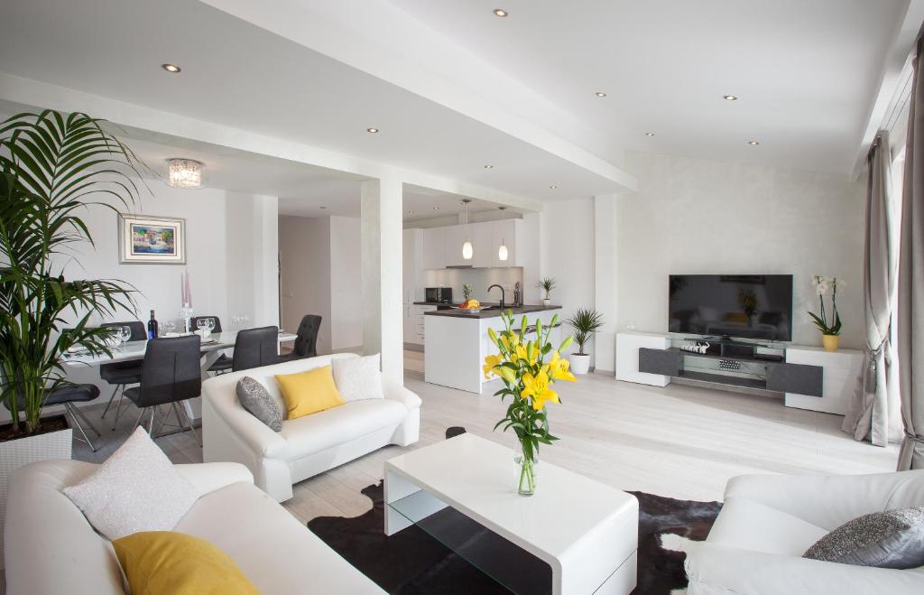 a living room with white furniture and a living room with yellow flowers at Modern Apartman Pjero in Makarska